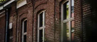 Une façade en briques rouges avec des fenêtres à double vitrage reflétant la lumière naturelle.